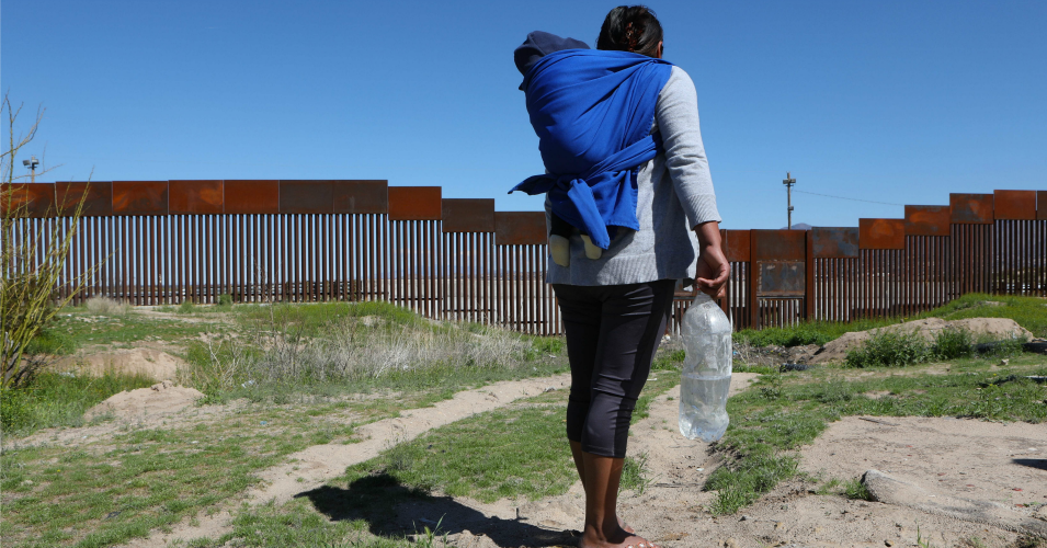 A migrant carrying a toddler stands in front of the border wall that divides Sunland Park, New Mexico, United States, with Ciudad Juarez, state of Chihuahua, Mexico on March 14, 2020. - April 22, 2020 commemorates the 50th anniversary of the World Earth Day. (Photo: Herika Martinez/AFP via Getty Images)