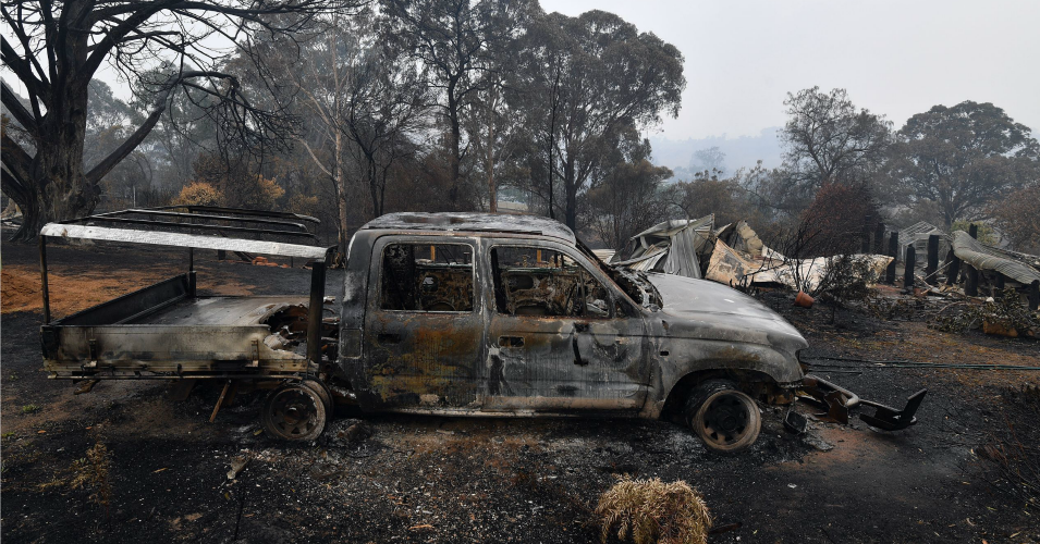 A woodchip mill burnt by bushfires is seen as smoke rises in Quaama in Australia's New South Wales state on January 6, 2020. - Reserve troops were deployed to fire-ravaged regions across three Australian states on January 6 after a torrid weekend that turned swathes of land into smouldering, blackened hellscapes. (Photo by SAEED KHAN / AFP)
