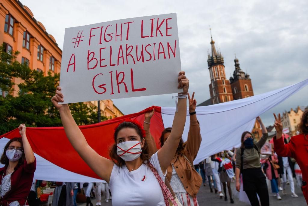 A demonstrator dressed in white wears a protective face mask and holds a banner during the "You go girl! Women's march for Belarus" on October 10, 2020 in Krakow, Poland. The women March for Belarus is a global action to show solidarity with thousands of Belarusian women, clad in white and holding flowers who have been victims of police violence and inhuman detention by the police during protests. (Photo by Omar Marques/Getty Images)
