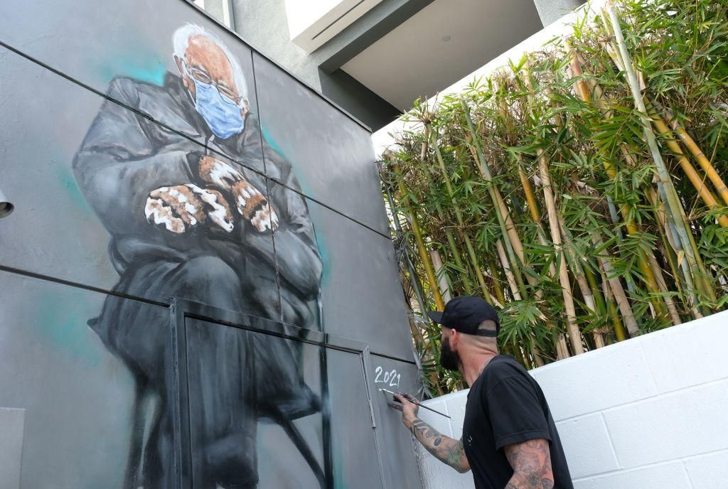 Artist Jonas Never (@never1959) applies finishing touches to his mural of Senator Bernie Sanders in Culver City, California on January 24, 2021. Standing out in a crowd of glamorously dressed guests, Bernie Sanders showed up for the US presidential inauguration in a heavy winter jacket and patterned mittens—with an AFP photo of the veteran leftist spawning the first viral meme of the Biden era. (Photo by CHRIS DELMAS/AFP via Getty Images)