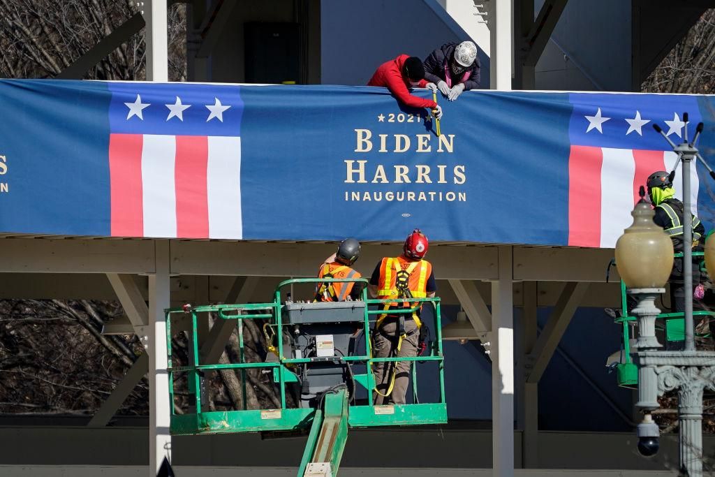 Workers put up "Biden-Harris" branded bunting on a press riser along the inaugural parade route near the White House on January 14, 2021 in Washington, DC. Thousands of National Guard troops have been activated to protect the nation's capital against threats surrounding President-elect Joe Biden's inauguration and to prevent a repeat of last weeks deadly insurrection at the U.S. Capitol. (Photo by Drew Angerer/Getty Images)