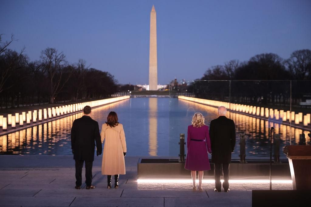 Douglas Emhoff, U.S. Vice President-elect Kamala Harris, Dr. Jill Biden and U.S. President-elect Joe Biden look down the National Mall as lamps are lit to honor the nearly 400,000 American victims of the coronavirus pandemic at the Lincoln Memorial Reflecting Pool January 19, 2021 in Washington, DC. As the nation's capital has become a fortress city of roadblocks, barricades and 20,000 National Guard troops due to heightened security around Biden's inauguration, 400 lights were placed around the Reflecting 
