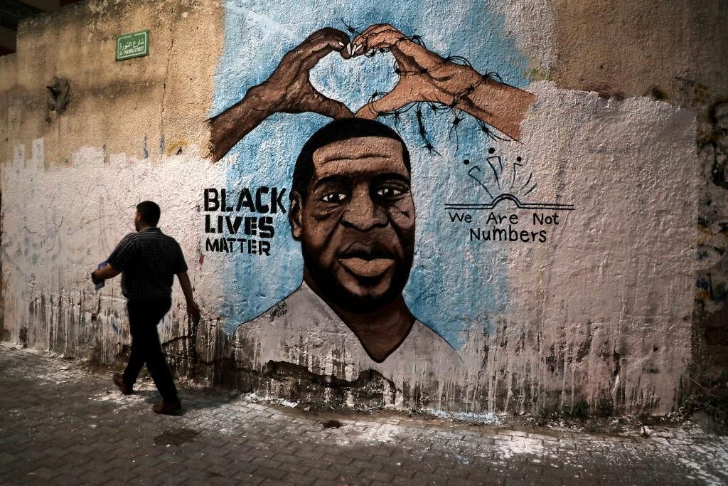 Palestinians walk past a mural of George Floyd, a black American who died after being restrained by police officers, in Gaza City, Tuesday, June 16, 2020. (Photo by Majdi Fathi/NurPhoto via Getty Images)