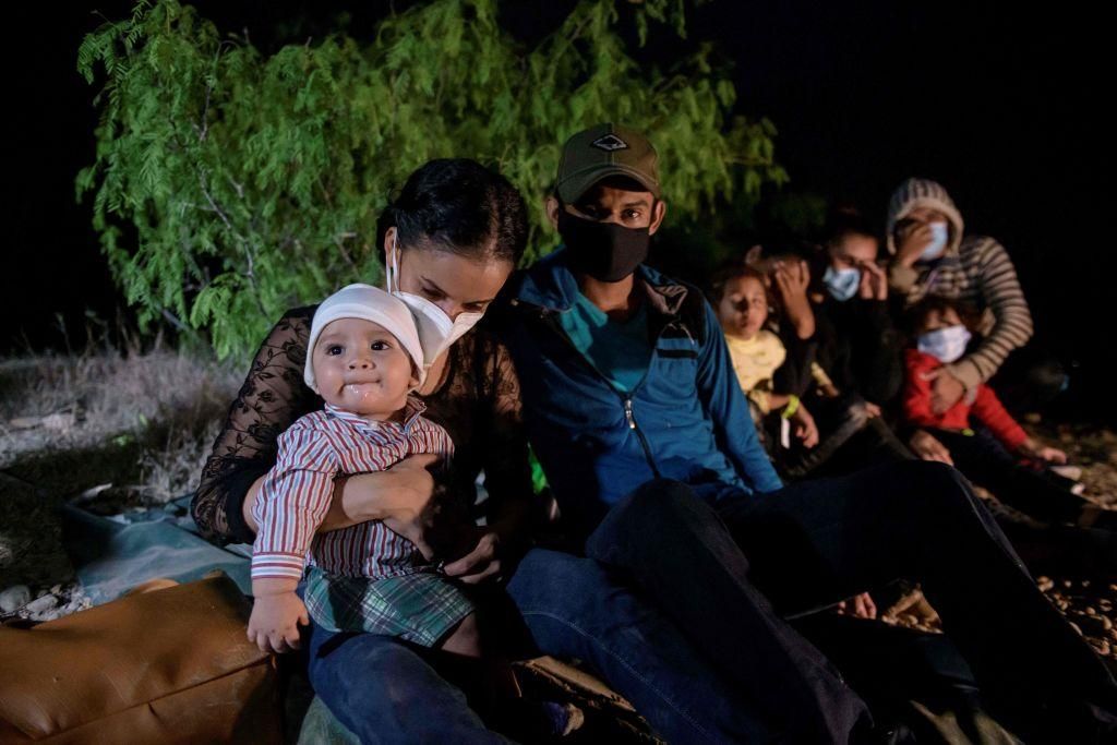 In a photo taken on March 27, 2021 immigrants from Honduras, who arrived illegally across the Rio Grande river from Mexico, rest on the US side of the river bank following their crossing, before making their way towards a makeshift processing checkpoint in the border city of Roma. (Photo: ED JONES/AFP via Getty Images)