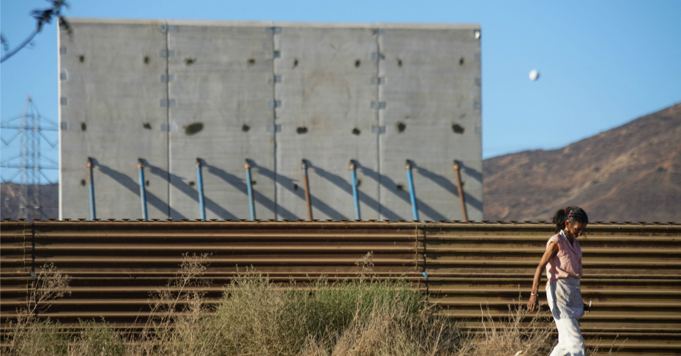 A woman walk past prototype sections of a border wall between Mexico and the United States under construction on October 5, 2017 in Tijuana, Mexico. (Photo: Sandy Huffaker/Getty Images)
