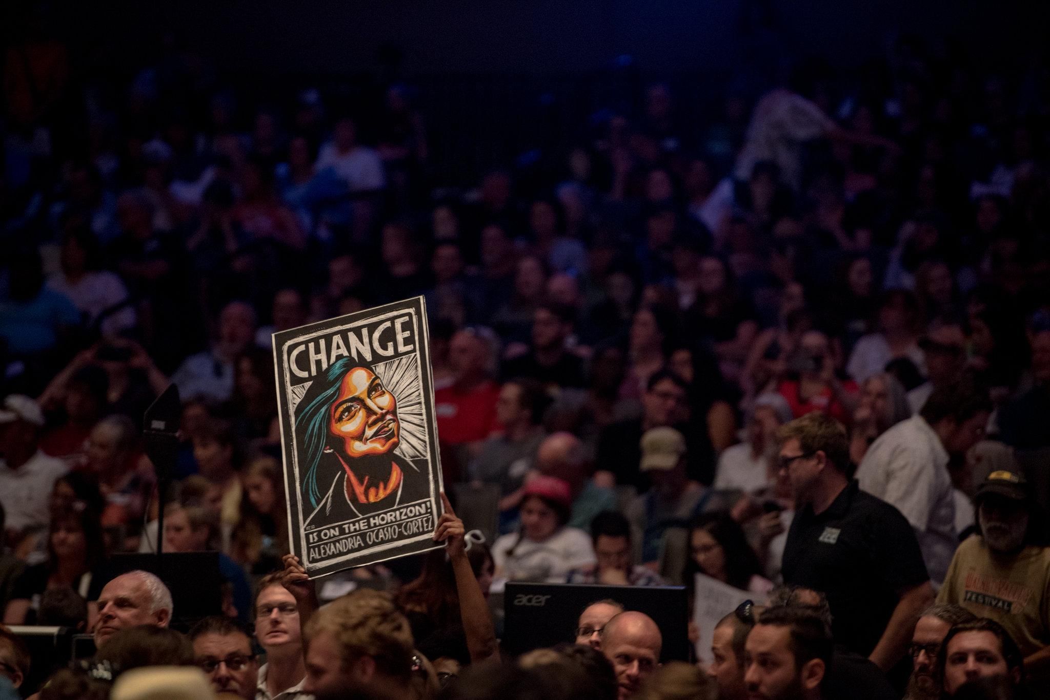 At a rally last week in Wichita, Kan., for James Thompson, a Democratic House candidate for a House seat, an audience member displayed a sign portraying Alexandria Ocasio-Cortez, a member of the Democratic Socialists of America and Democratic nominee for a House seat in New York City. (Photo: Hilary Swift for The New York Times) 