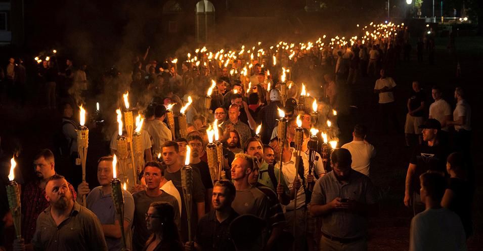 White nationalists march at the University of Virginia "Unite the Right" rally in Charlottesville in 2017. The marchers carried tiki torches and chanted Nazi slogans including "Jews Will Not Replace Us, " "Sieg Heil," and "Blood and Soil" while giving the Nazi salute.