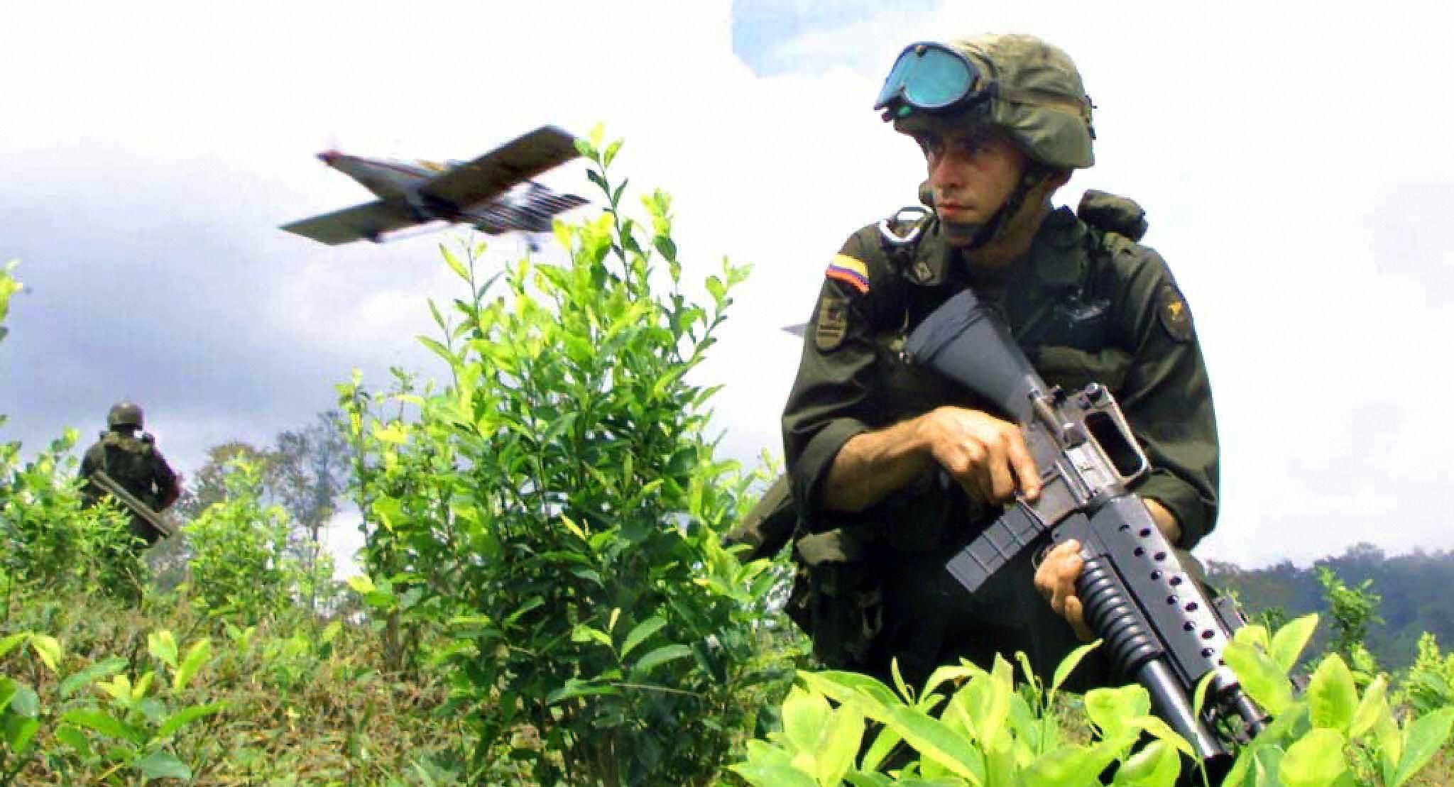 Colombian soldier advances in a field of cocaine while a plane sprays glyphosate. The Colombian government is continuing the fumigation of illegal crops despite the protest of indigenous communities and local authorities because the herbicides ruin other crops and the water.