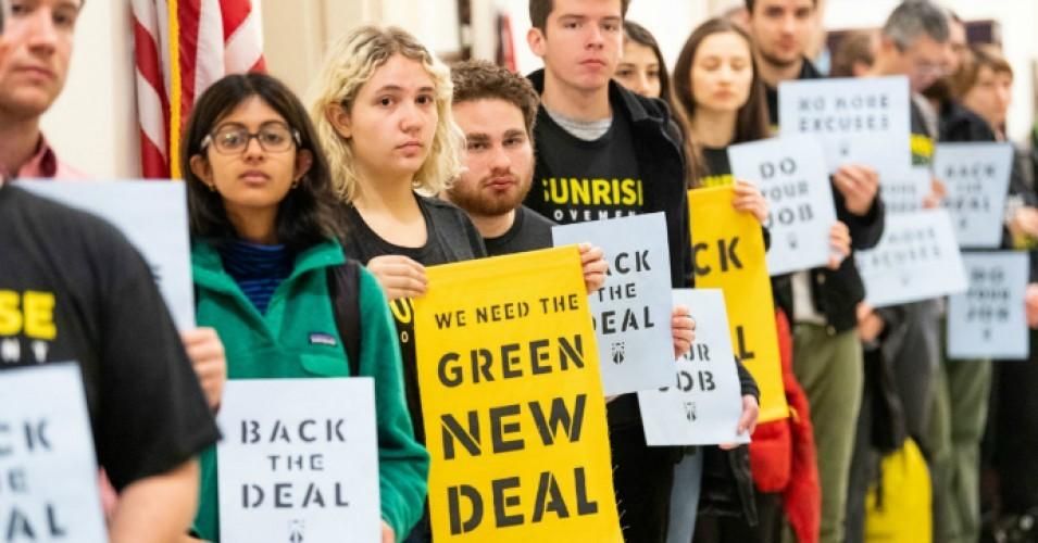 Activists hold signs calling for a Green New Deal