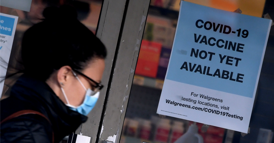 A woman walks past a "Covid-19 vaccine not yet available" sign outside a store in Arlington, Virginia on December 1, 2020. (Photo: Olivier Douliery/AFP via Getty Images)