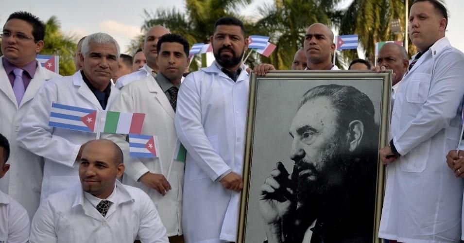 Doctors and nurses of Cuba's Henry Reeve International Medical Brigade pose with a portrait of Cuban late leader Fidel Castro as they are bid farewell before travelling to hard-hit Italy to help in the fight against the coronavirus COVID-19 pandemic, at the Central Unit of Medical Cooperation in Havana, on March 21, 2020. (Photo: Yamil LAGE / AFP via Getty Images)