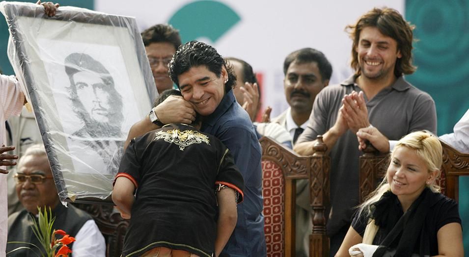 Argentina's national football team coach and former football star Diego Armando Maradona (C) greets the young artist who painted and presented him with a portrait of revolutionary Che Guevara, as Maradona's girlfriend Veronica (R) looks on during the laying of the foundation stone for the Indian Football School at Maheshtala, on the outskirts of Kolkata on December 6, 2008