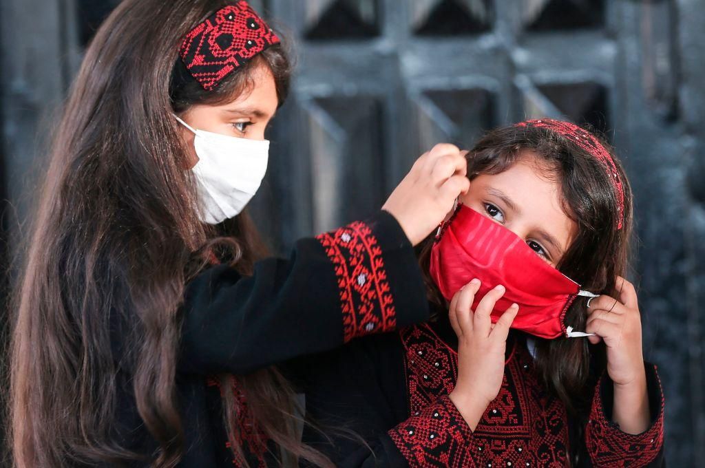 Palestinian girls wearing protective masks attend a graduation ceremony from the Police Academy amid concerns about the spread of the coronavirus COVID-19 in Gaza City on May 7, 2020. (Photo by MAHMUD HAMS/AFP via Getty Images)