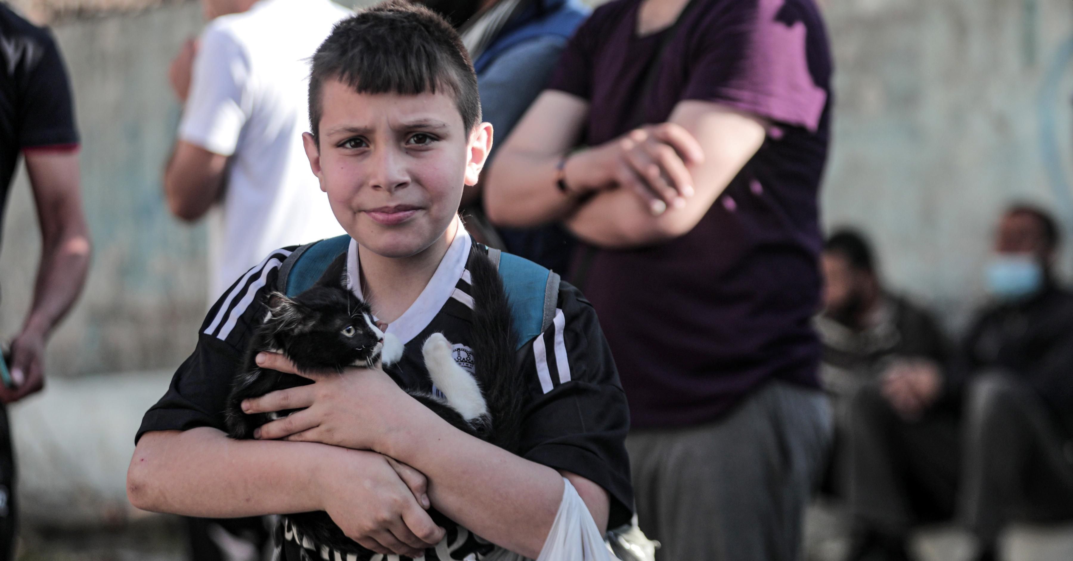 A Palestinian child carries his cat after he and his family members survived the violent Israeli bombing of their homes in Gaza City, on May 16, 2021. (Photo: Momen Faiz/NurPhoto via Getty Images)