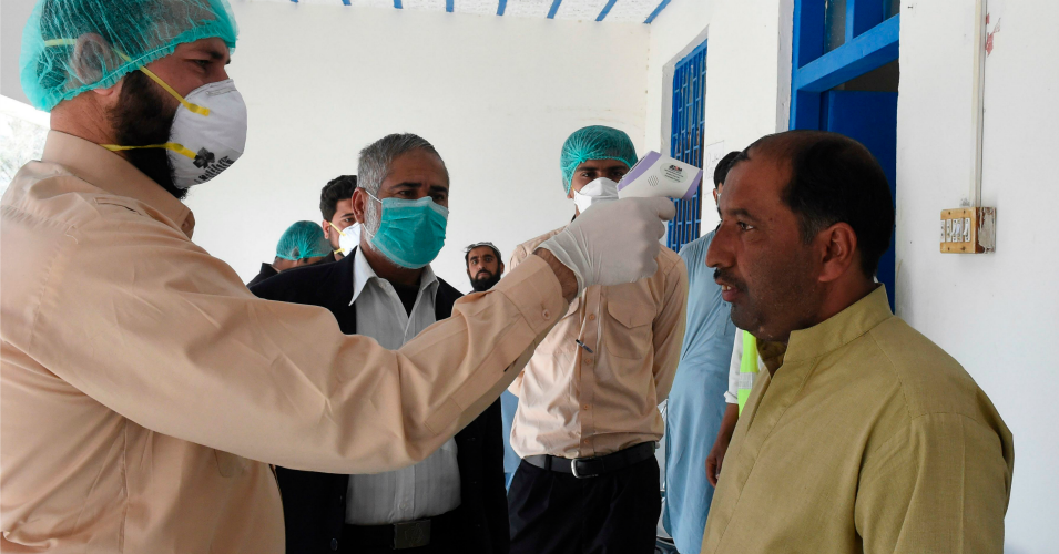 A doctor checks the body temperature of a man returning from Iran at a quarantine zone to test for the COVID-19 coronavirus in the Pakistan-Iran border town of Taftan on February 25, 2020. (Photo: Banaras Khan/AFP via Getty Images)