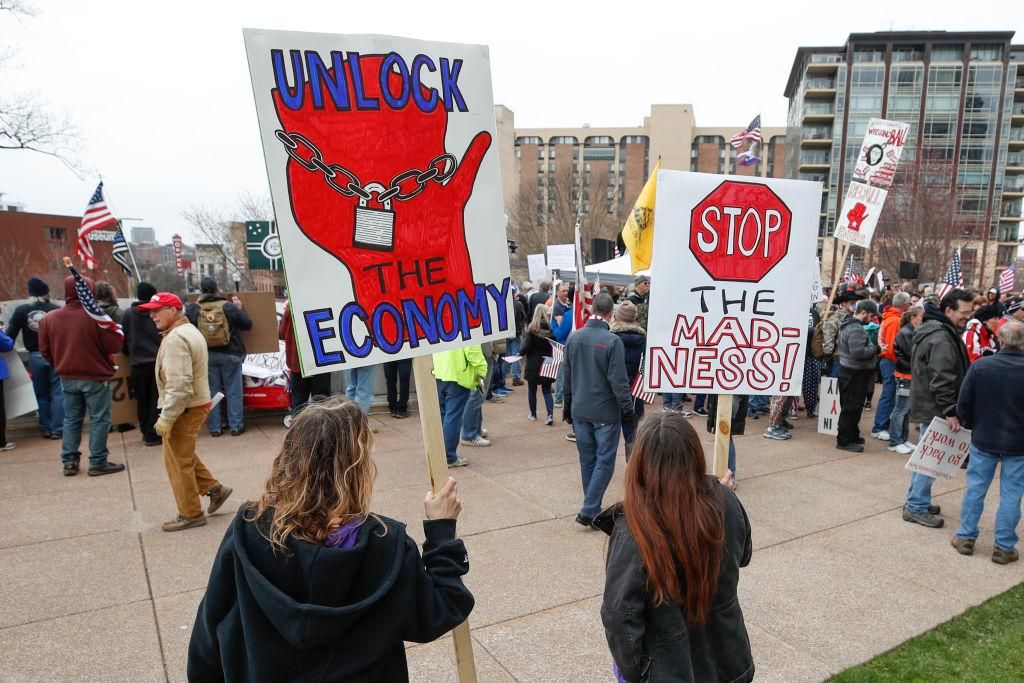People hold signs during a protest against the coronavirus shutdown in front of the State Capitol in Madison, Wisconsin, on April 24, 2020. (Photo by KAMIL KRZACZYNSKI/AFP via Getty Images)