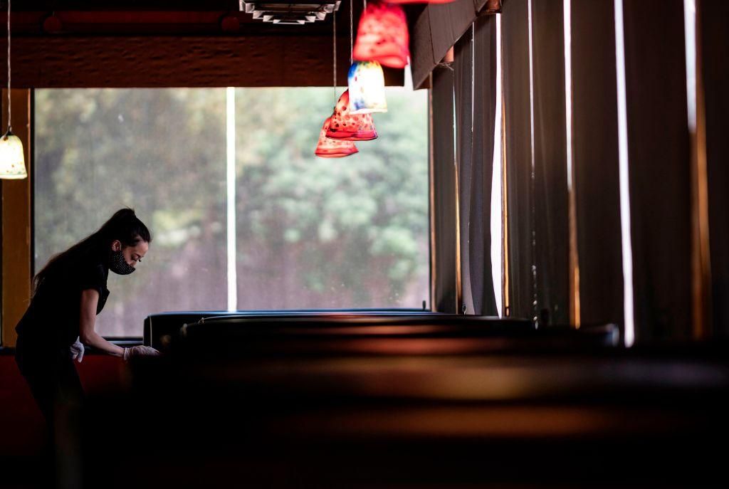A waitress wearing a mask and gloves disinfects a table in a restaurant in Stillwater, Oklahoma. (Photo: JOHANNES EISELE/AFP via Getty Images)