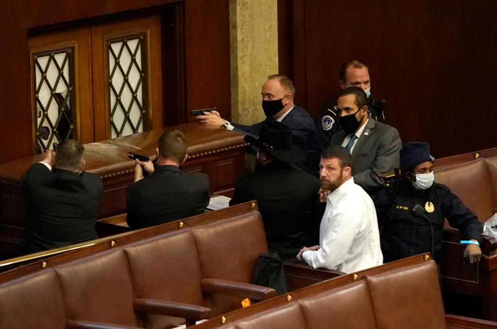 U.S. Capitol police officers point their guns at a door that was vandalized in the House Chamber during a joint session of Congress on January 06, 2021 in Washington, DC. Congress held a joint session today to ratify President-elect Joe Biden's 306-232 Electoral College win over President Donald Trump. A group of Republican senators said they would reject the Electoral College votes of several states unless Congress appointed a commission to audit the election results. (Photo by Drew Angerer/Getty Images)