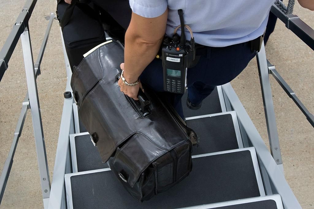 A U.S. Air Force military aide carry "The Football" off Air Force One in Raleigh, NC. The Football is a specially outfitted black briefcase used by the President of the United States to authorize the use of nuclear weapons. The specific contents of the briefcase are highly classified and have lead to much speculation. It reportedly holds a secure satellite communication (SATCOM), and other materials that the president would rely on should a decision to use nuclear weapons need to be made. (Photo by Brooks K