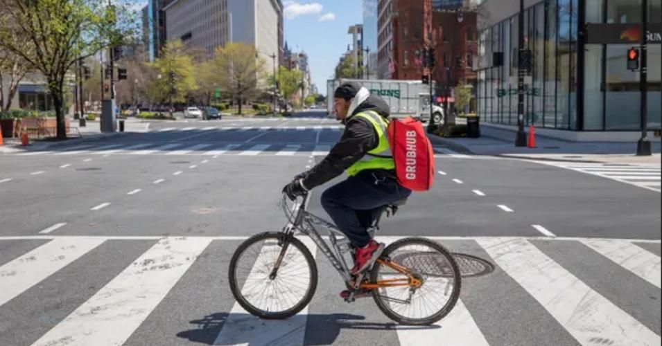 A Grubhub delivery person makes bicycle deliveries on the empty streets of Washington DC. (Photograph: Erik S Lesser/EPA)