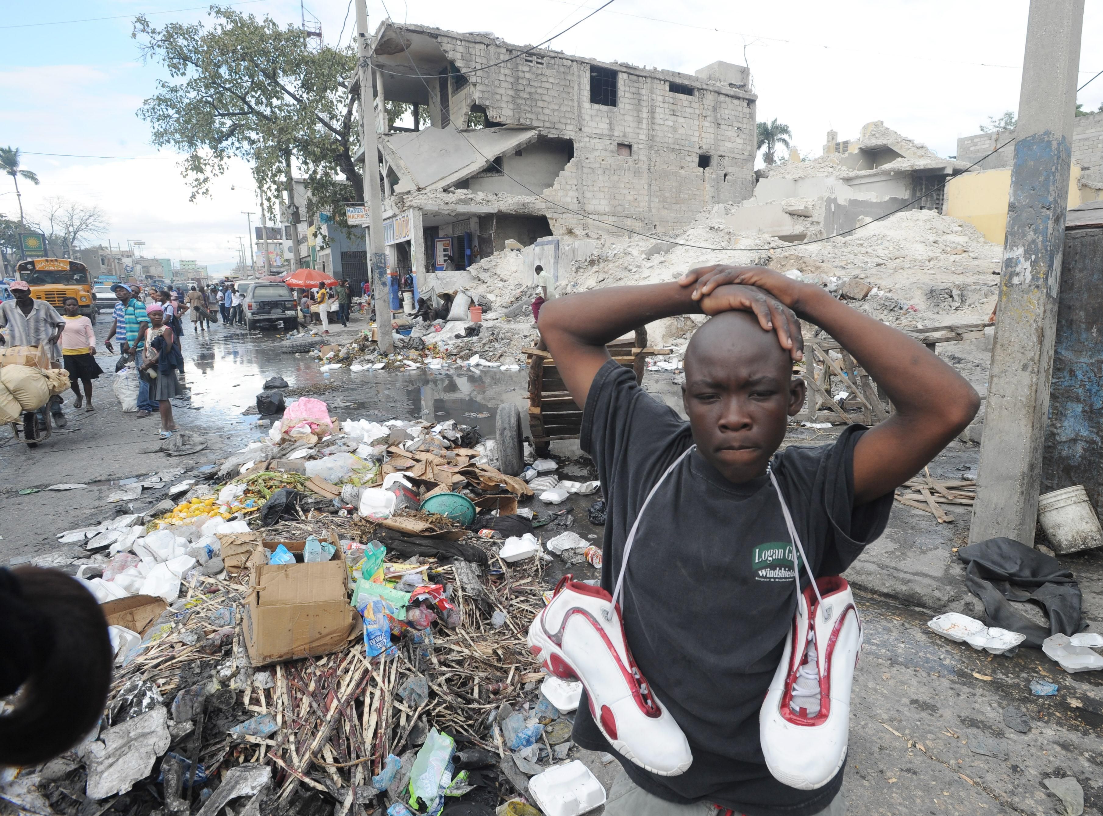 A Haitian man sells used shoes in Port-au-Prince amidst earthquake damage on January 9, 2012. (Photo: THONY BELIZAIRE/AFP via Getty Images)