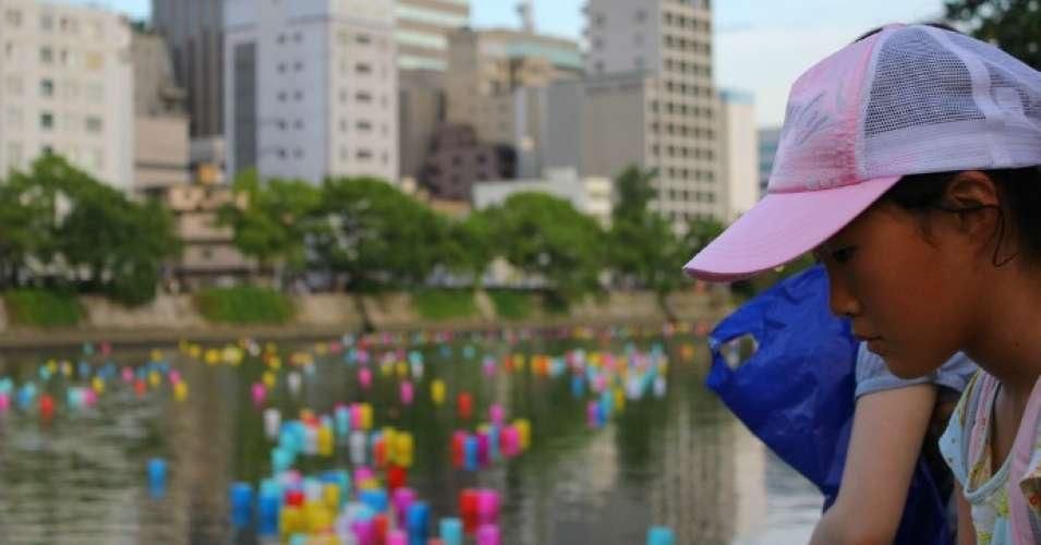 A young person's solemn face appears in front of the 2011 Hiroshima Lantern Festival marking the atomic bomb. (Photo: Richard Riley/flickr/cc)