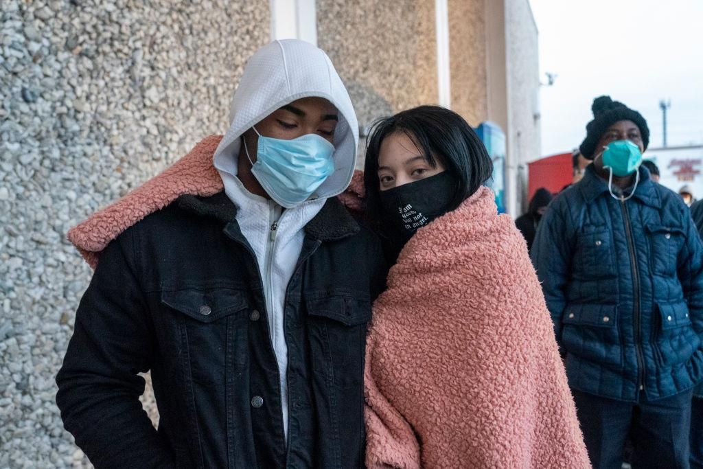 Junior Ceqara and Alexa Albare share a blanket to keep warm while standing in line to enter Fiesta supermarket on February 16, 2021 in Houston, Texas. Winter storm Uri has brought historic cold weather, power outages and traffic accidents to Texas as storms have swept across 26 states with a mix of freezing temperatures and precipitation. (Photo by Go Nakamura/Getty Images)