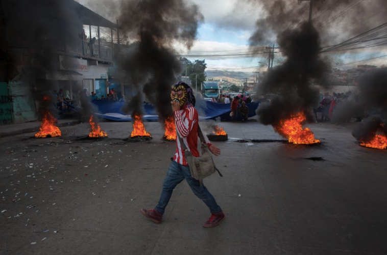A protester walks by a barricade of burning tires in the neighborhood of Villanueva in Tegucigalpa, Honduras on December 15, 2017.