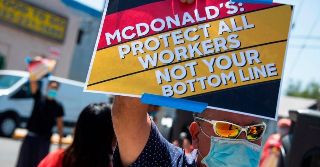 McDonald's workers and their supporters hold signs at a rally to protest what they allege is McDonald's attempts to silence a worker who spoke out about unsafe conditions amid the COVID-19 pandemic, August 7, 2020 outside a McDonald's in Los Angeles, California. (Photo by Robyn Beck / AFP via Getty Images) 