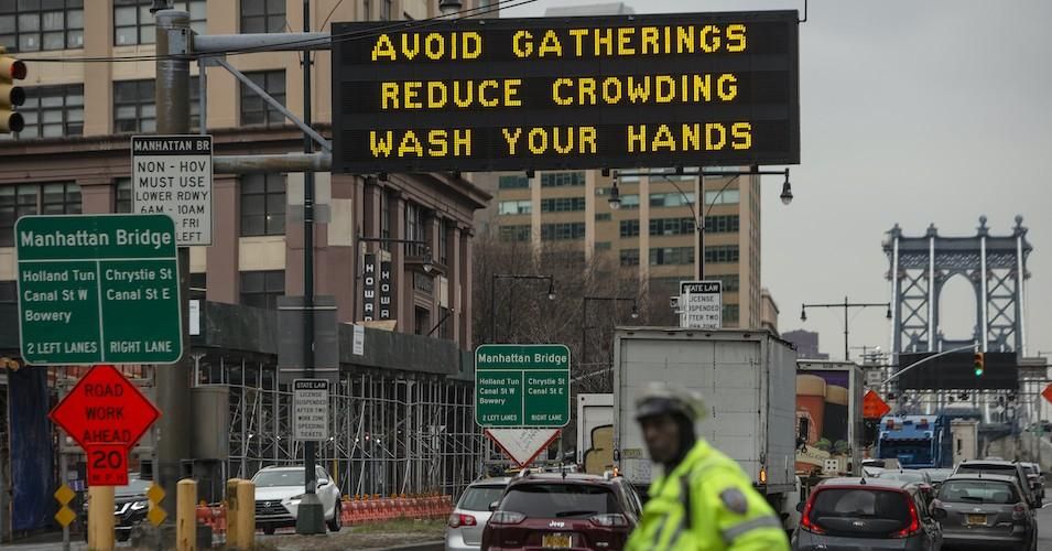 A sign warns residents to take steps to contol the coronavirus outbreak at the entrance to the Manhattan Bridge in Brooklyn on March 19, 2020 in New York City.