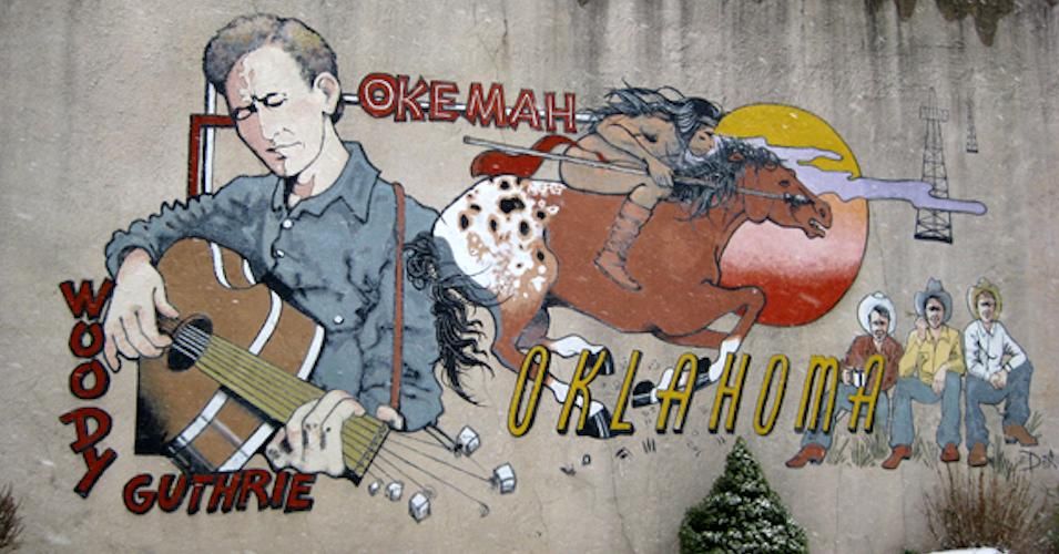 Mural at 510 West Broadway, Hwy. 56, downtown Okemah, Oklahoma, depicting Woody Guthrie and Okfuskee County history. Painted by DeAnna Mauldin in 1994.