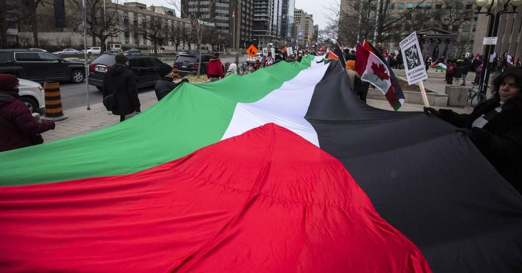 Protesters hold a giant Palestinian flag as they walk across University Avenue during a demonstration in Toronto, Canada, December 9, 2017. (Photo by Giordano Ciampini/Anadolu Agency/Getty Images)