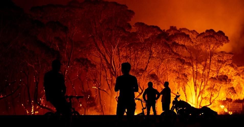 Residents look on as wildfires burn through bush on January 4, 2020 in Lake Tabourie, Australia.
