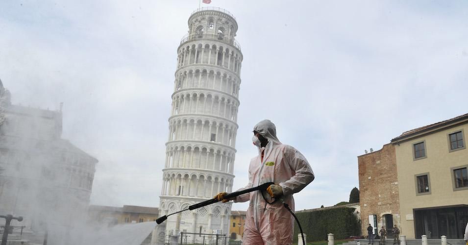 A worker carries out sanitation operations for the Coronavirus emergency in Piazza dei Miracoli near to the Tower of Pisa in a deserted town on March 17, 2020.
