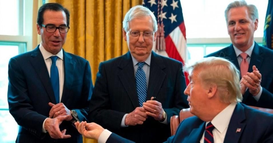 President Donald Trump hands out pens to Treasury Secretary Steven Mnuchin (L) and Senate Majority Leader Mitch McConnell (C) after signing the CARES act, a $2 trillion rescue package to provide economic relief amid the coronavirus outbreak, at the Oval Office of the White House on March 27, 2020. (Photo: Jim Watson/AFP via Getty Images)