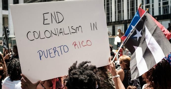 protester holds sign that say end colonialism in Puerto Rico 