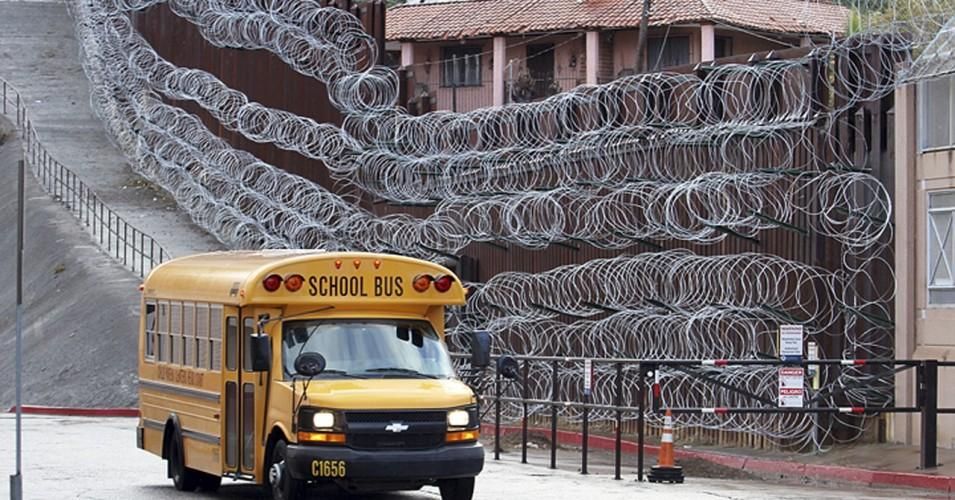In this Monday, Feb. 4, 2019 photo, a school bus rolls past the razor wire-covered fence at East International and Nelson Streets in downtown Nogales, Ariz. (Photo: Jonathan Clark/Nogales International via AP)
