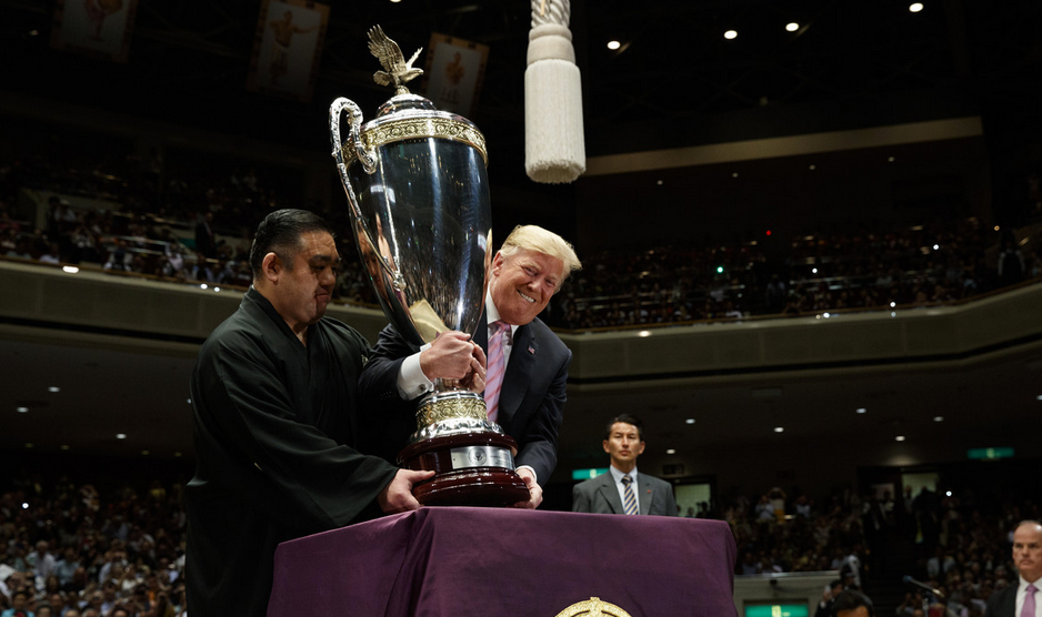 President Donald Trump lifts the "President’s Cup" to present it to Tokyo Grand Sumo Tournament winner Asanoyama at Ryogoku Kokugikan Stadium on Sunday. (Photo: Evan Vucci/AP)