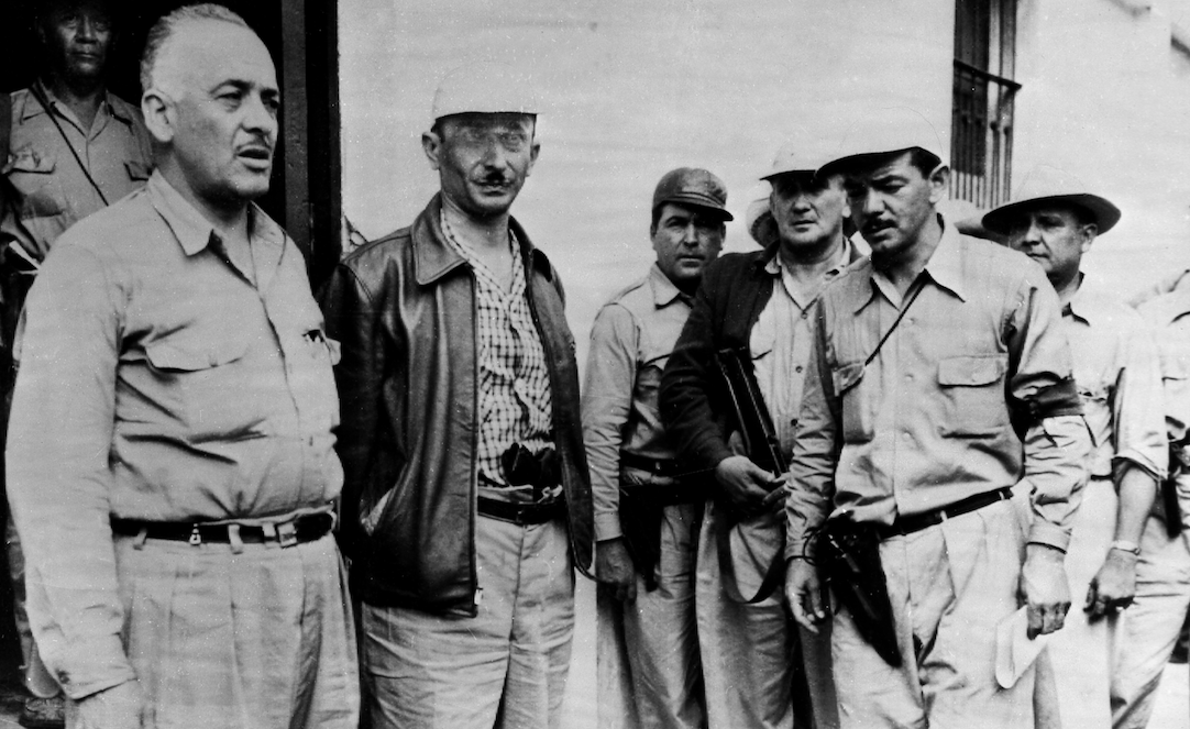 GUATEMALA COUP, 1954. Colonel Miguel Mendoza, Colonel Carlos Castillo Armas, and Major Julio Gaitan (foreground, left-to-right), three leaders of the rebel invasion force which overthrew the government of President Jacobo Arbenz Guzman of Guatemala in 1954. Photographed 24 June 1954. (Photo: ullstein bild via Getty Images)