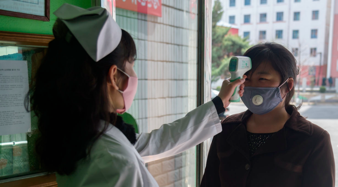 A health worker takes the temperature of a woman amid concerns over the COVID-19 coronavirus at an entrance of the Pyongchon District People's Hospital in Pyongyang on April 1, 2020. (Photo: Kim Won Jin / AFP via Getty Images)