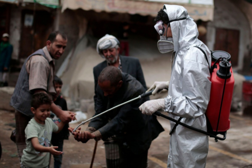 Sanaa, Yemen. 30th Apr, 2020. A health worker wearing a protective suit sprays disinfectant on the hands of people at a market in the old city of Sanaa, amid concerns of the spread of the coronavirus (COVID-19). (Photo: Hani Al-Ansi/dpa/Alamy Live News.)