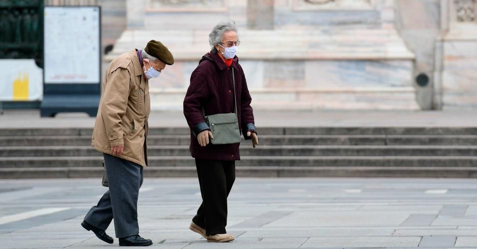 An elderly couple wearing protective masks walk across a deserted Duomo square in Milan on March 31, 2020, during the country's lockdown aimed at curbing the spread of the COVID-19 infection, caused by the novel coronavirus. (Photo: Miguel Medina / AFP via Getty Images)