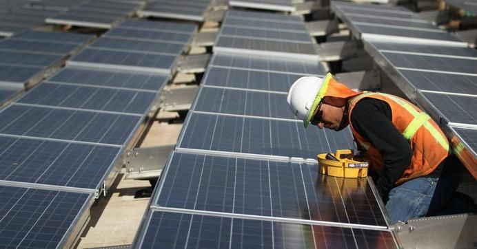 A worker installs solar panels atop a government building in Lakewood, Colo. The industry has added more than 80,000 jobs since 2010, according to The Solar Foundation.