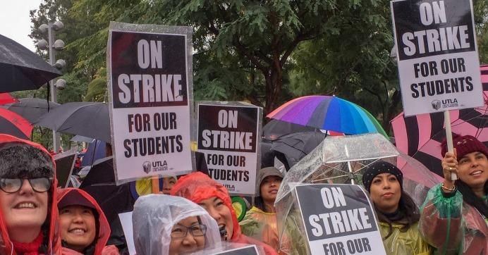 A crowd holds signs reading "On strike for our students."