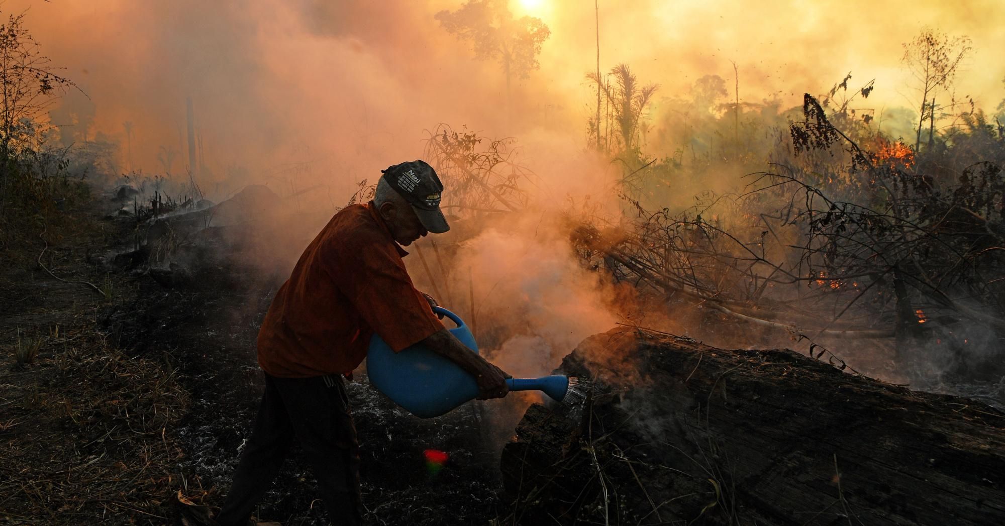 A farmer tries to pour water on an area close to an illegally lit fire in the Amazon rainforest, south of Novo Progresso in the Brazilian state of Pará on August 15, 2020. (Photo: Carl de Souza/AFP via Getty Images)