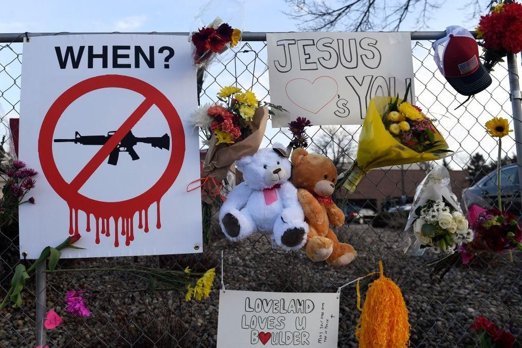 A sign calling for a ban on assault rifles, along with mementos and flowers, hangs from the perimeter fence outside a King Soopers grocery store in Boulder, Colorado on March 24, 2021, to honor the ten people killed during a mass shooting at a King Soopers grocery store. (Photo: JASON CONNOLLY/AFP via Getty Images)