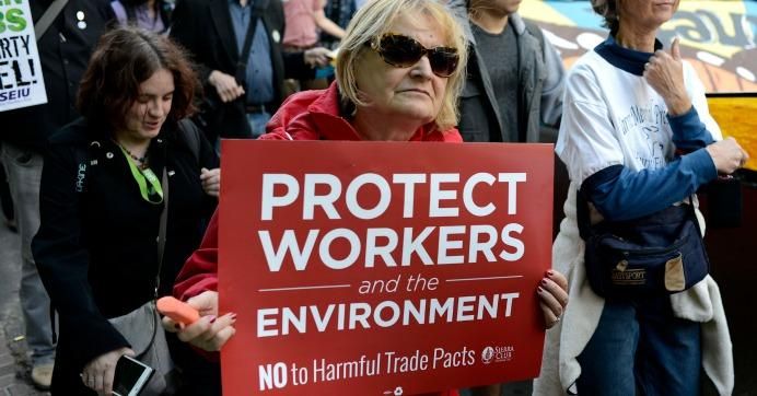Protester holds a sign reading: Protect workers and the environment