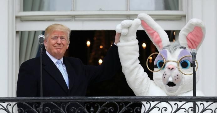 President Donald Trump (L) lifts the hand of a person in an Easter Bunny costume on the Truman Balcony during the 140th annual Easter Egg Roll on the South Lawn of the White House April 2, 2018 in Washington, D.C. 