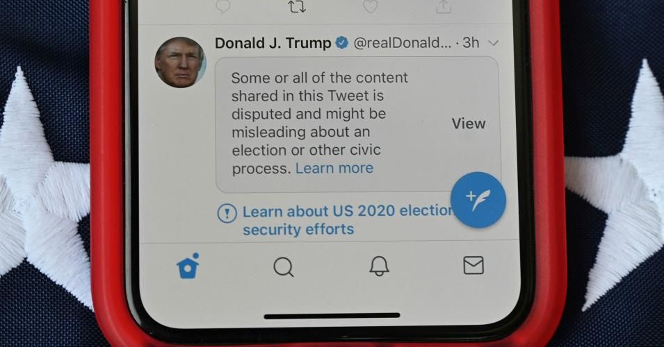 This illustration photo shows a mobile phone placed on a US flag with Tweets from US President Donald Trump masked with warnings imposed by Twitter stating that they may be incorrect, November 5, 2020 as vote counting continues to determine the winner of the presidential electionn. (Photo: Robyn Beck/AFP via Getty Images)