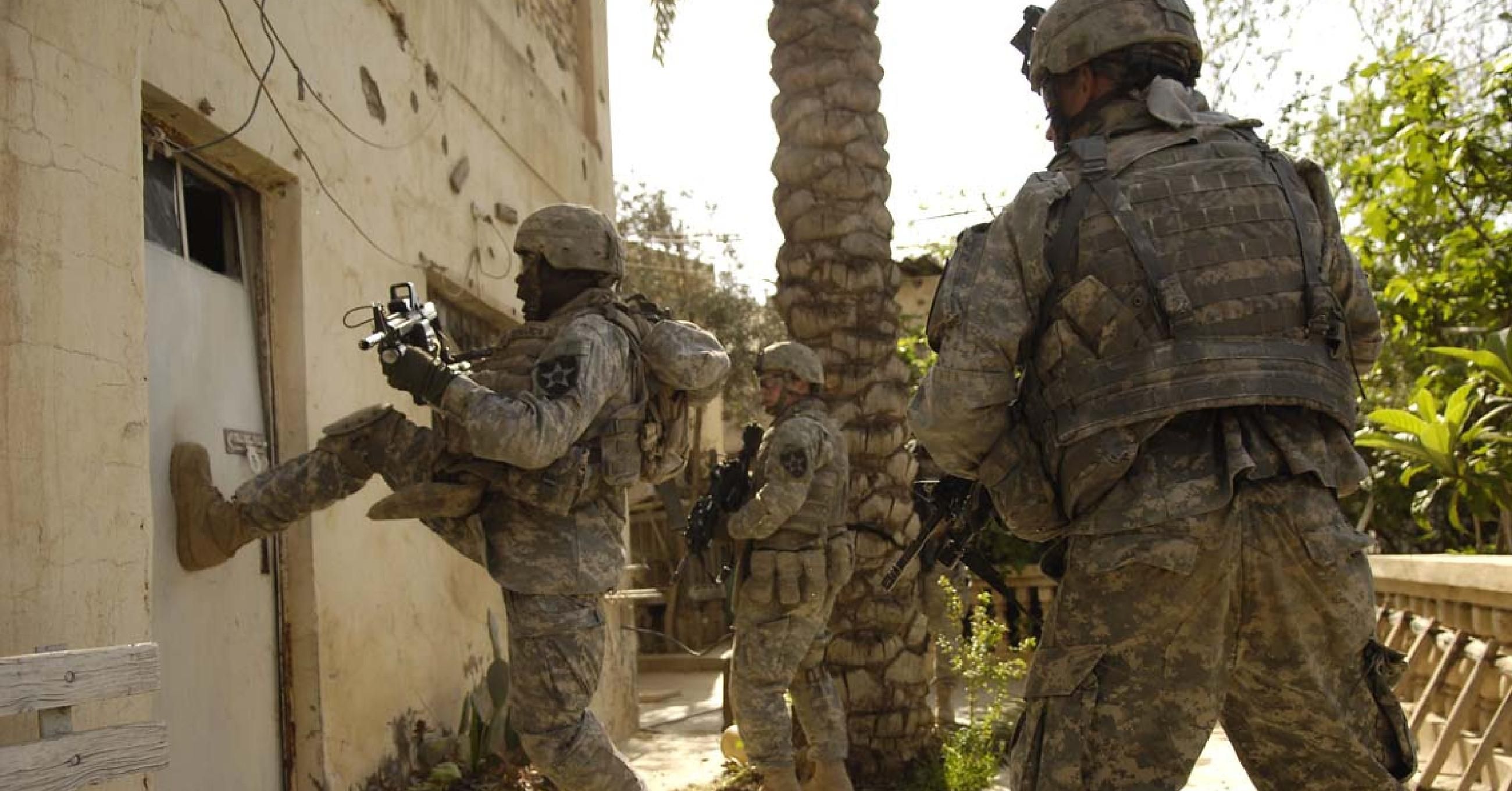 A U.S. Army Soldier from the 1st Stryker Brigade Combat Team kicks in the door of a building during a cordon and search in Buhriz, Iraq, March 14, 2007. (Photo: Staff Sgt. Stacy L. Pearsall/U.S. Air Force/Flickr)